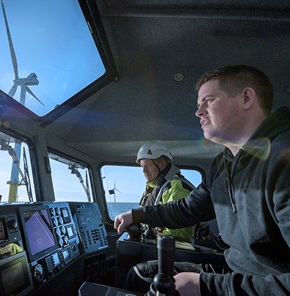 Two men navigating a commercial boat through the sea.