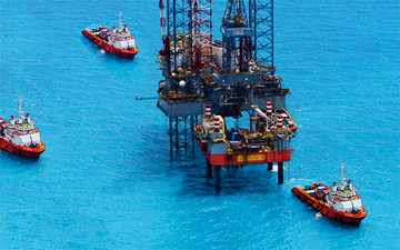 Oil rig in clear blue water, connected with offshore marine internet, surrounded by 3 boats 
