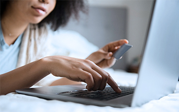 Woman holding a credit card, entering its number securely onto her laptop