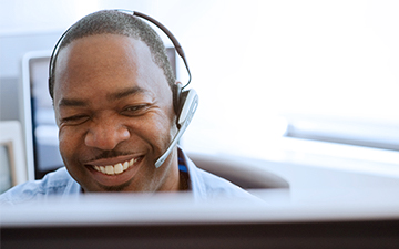  A customer support representative discussing internet packages wtih a customer on a headset, sitting behind a computer