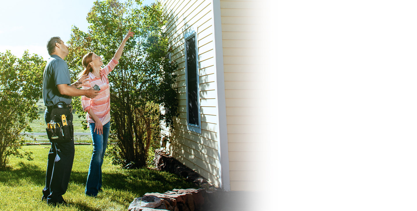 A woman pointing to the outside of her house, showing the technician where wants the satellite internet installation