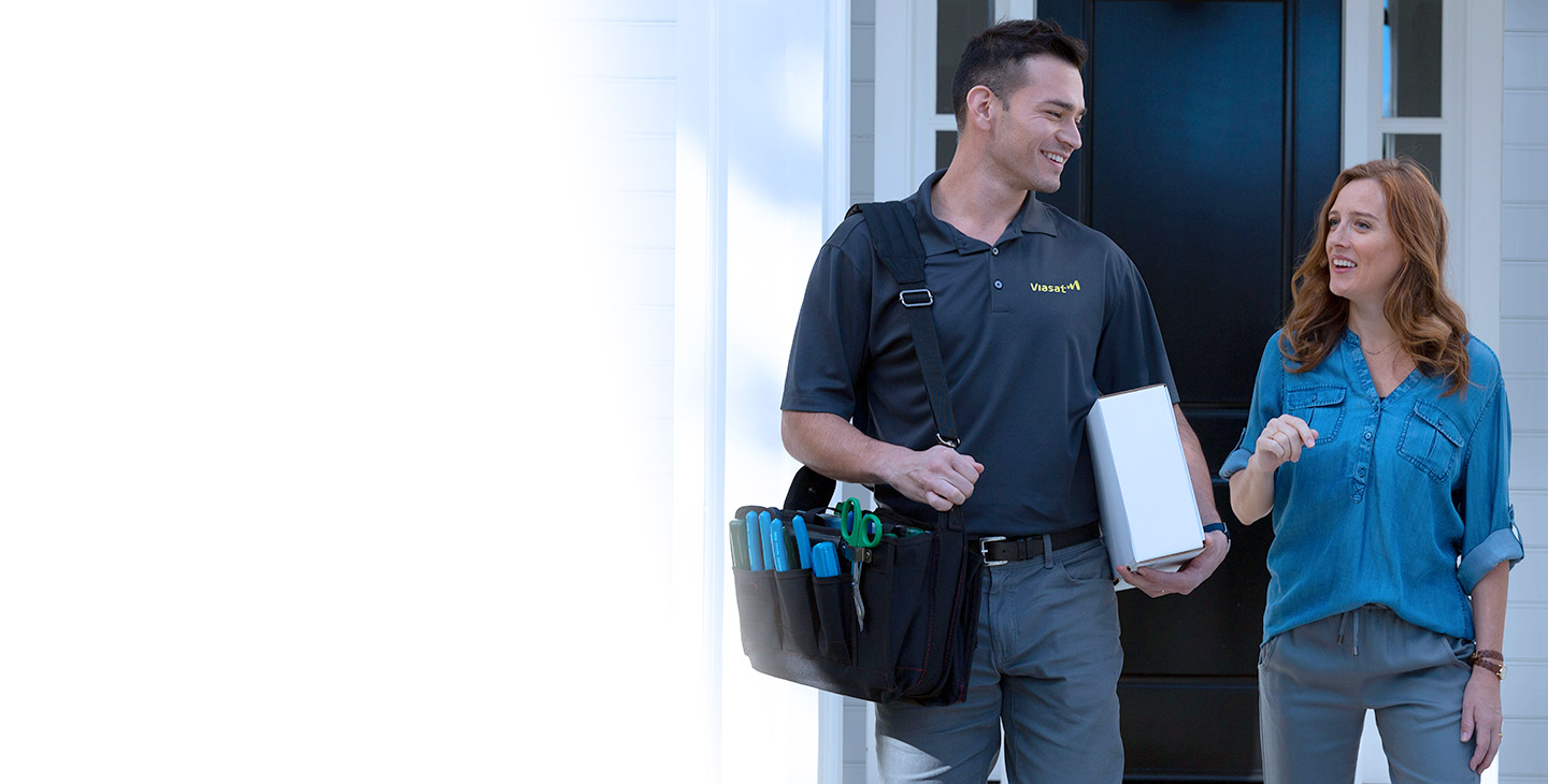 A satellite internet retailer with a bag around his shoulder smiling at a woman in front of her home