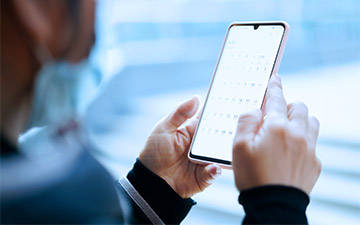 Close-up of hands holding a smart phone, protected by internet security software