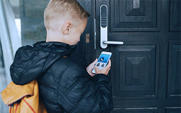 A young schoolboy has home internet security, standing in front of a door with a smartlock