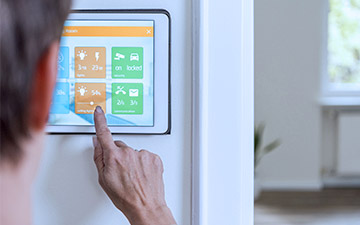 Close-up of a hand controlling a smart thermostat on the side of the wall
