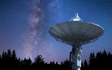 Image of a large ground station providing Viasat services, pointed up at a night sky filled with stars