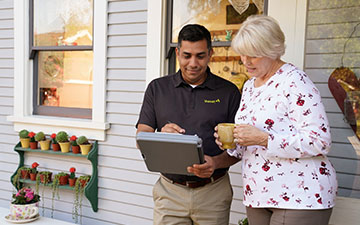 Viasat technician wearing a branded polo discussing Viasat services with a woman standing outside of her home