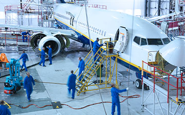 Group of nine airplane technicians wearing blue uniforms working on a plane