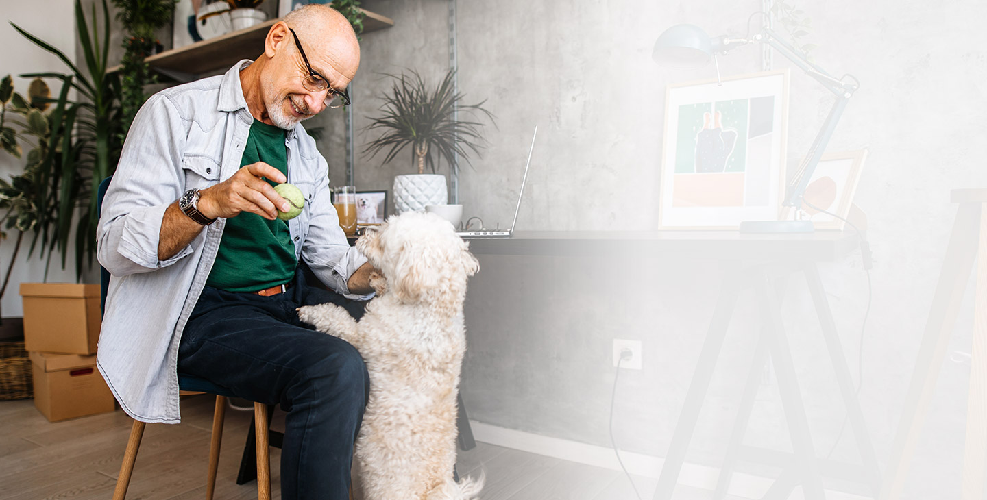 Man working from home takes a break to play with dog.