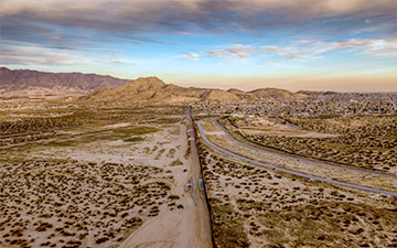 Image of desert land leading up to hills with a country's border running down the middle