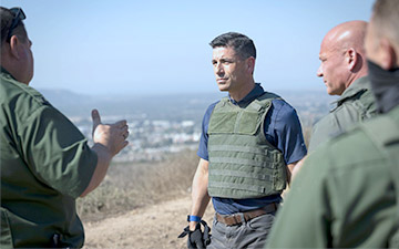 Group of four military personnel wearing green clothing talking out in the field